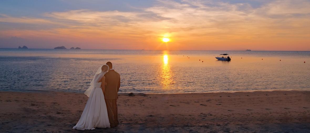 Newlyweds watching the sunset on the beach at The Sunset Beach Resort & Spa